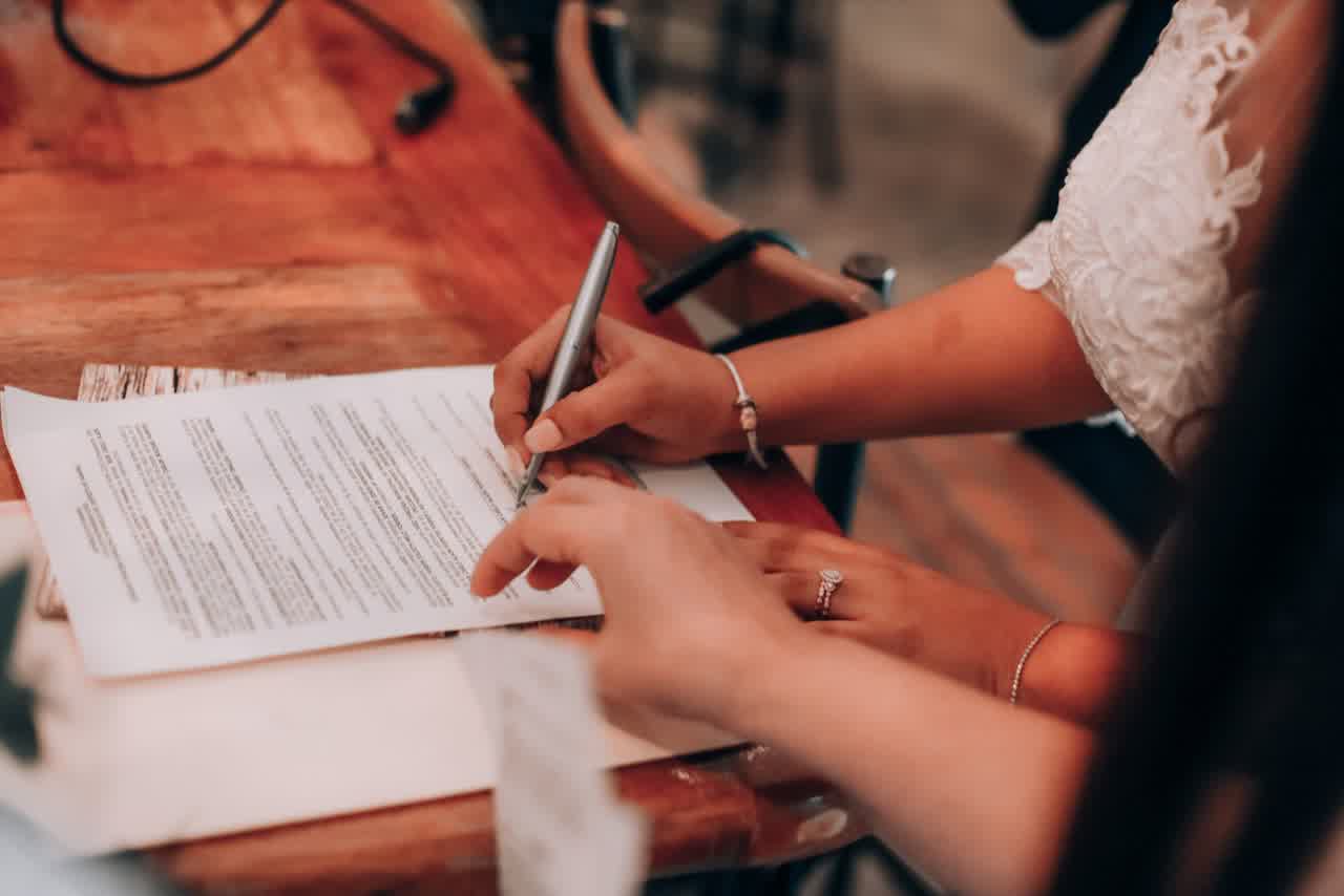 Manos revisando y firmando los formularios de un trámite migratorio
