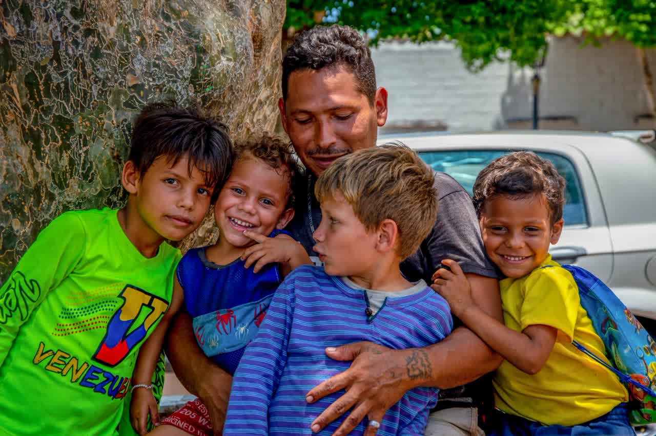 Padre abrazando a sus dos hijos adolescentes al aire libre